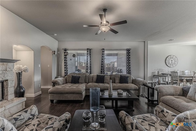 living room with a stone fireplace, ceiling fan, and dark hardwood / wood-style flooring