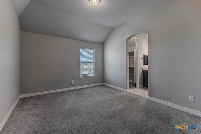 unfurnished room featuring light colored carpet and vaulted ceiling