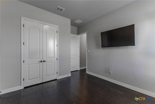 unfurnished bedroom featuring a closet and dark wood-type flooring