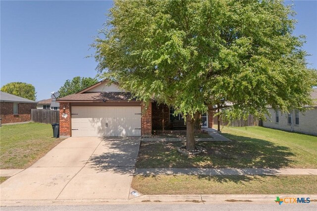 513 Leo Ln, Killeen, TX 76542 - obstructed view of property with driveway, an attached garage, a front lawn, brick siding, and fence