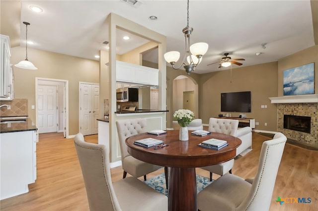 453 Raven Rdg, New Braunfels, TX 78130 - dining room with a ceiling fan, arched walkways, light wood finished floors, a brick fireplace, and recessed lighting