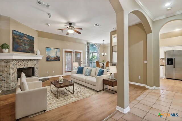 453 Raven Rdg, New Braunfels, TX 78130 - living room featuring ceiling fan, baseboards, a tiled fireplace, light wood-style floors, and ornamental molding