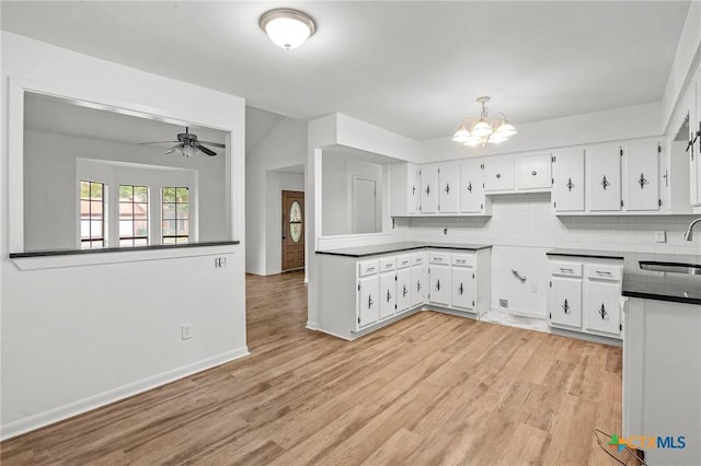 kitchen with white cabinets, ceiling fan with notable chandelier, sink, light wood-type flooring, and tasteful backsplash