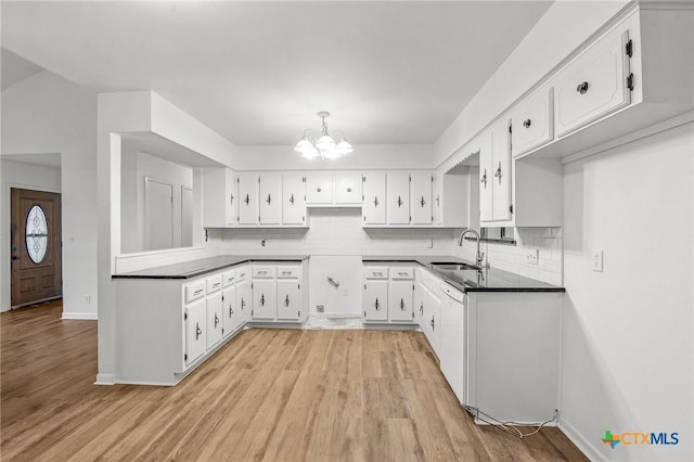 kitchen with decorative backsplash, white cabinetry, sink, and an inviting chandelier