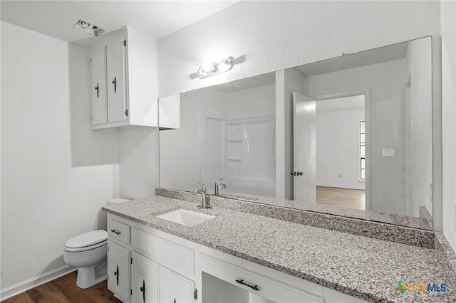 bathroom featuring a shower, vanity, wood-type flooring, and toilet