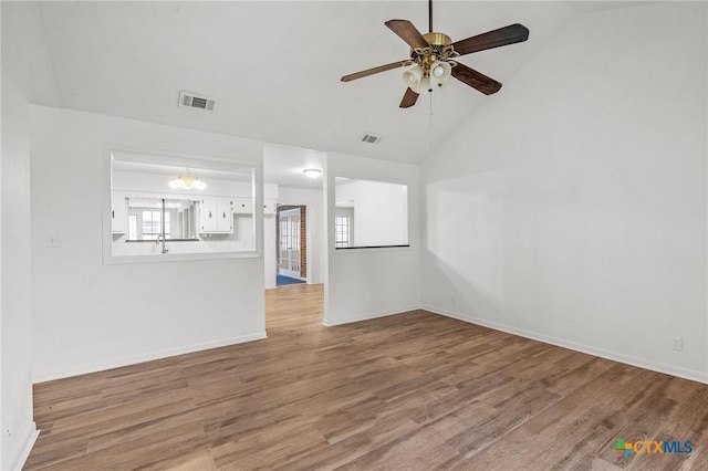 unfurnished living room with ceiling fan with notable chandelier, light hardwood / wood-style floors, vaulted ceiling, and sink