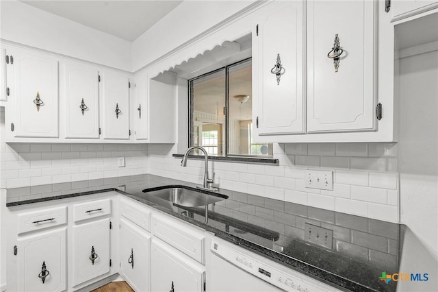 kitchen featuring tasteful backsplash, sink, dark stone countertops, dishwasher, and white cabinetry