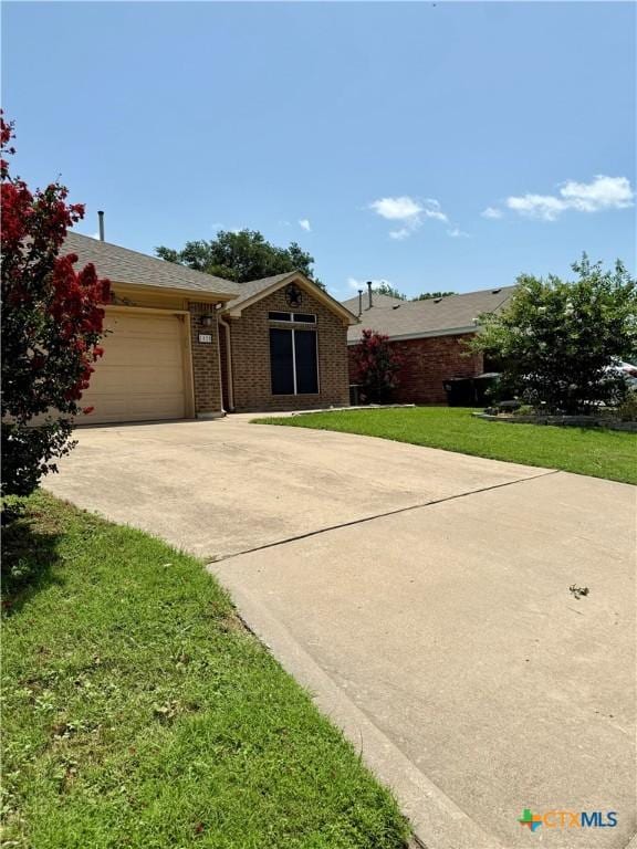 1828 Winchester Dr, Temple, TX 76502 - ranch-style house with concrete driveway, a garage, a front lawn, brick siding, and a shingled roof