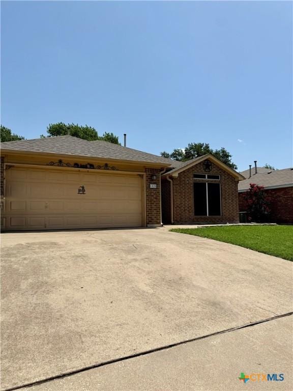 1828 Winchester Dr, Temple, TX 76502 - single story home featuring driveway, a garage, brick siding, a shingled roof, and a front lawn