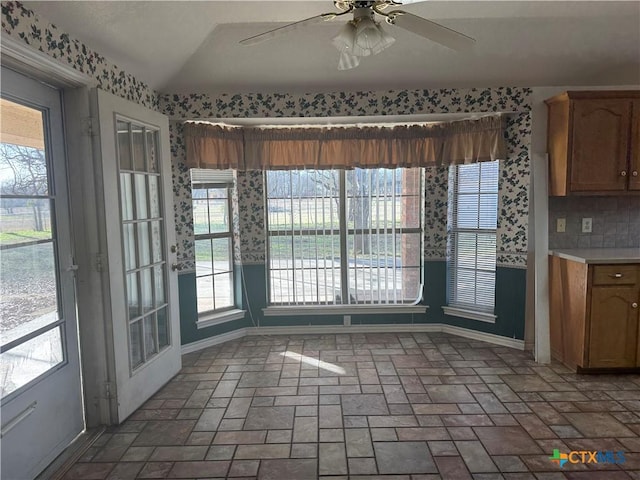 unfurnished dining area featuring vaulted ceiling, brick floor, and a ceiling fan