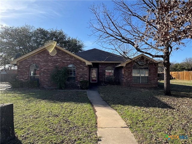 ranch-style house with a front yard, fence, and brick siding