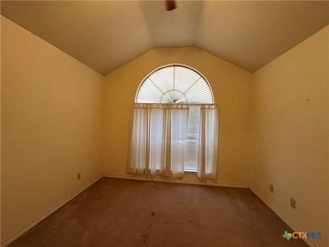 carpeted spare room featuring lofted ceiling and baseboards