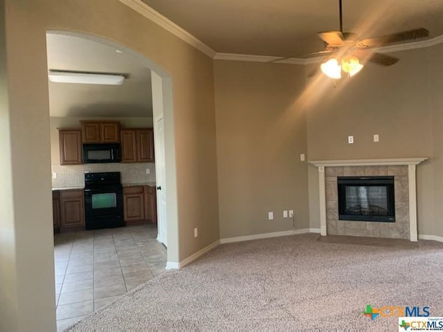 unfurnished living room featuring ceiling fan, light colored carpet, crown molding, and a tile fireplace