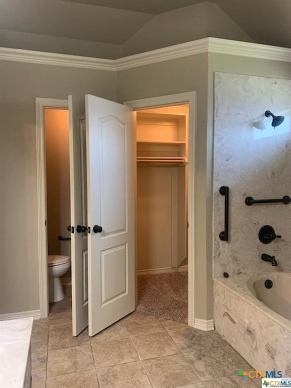 bathroom with crown molding, a relaxing tiled tub, lofted ceiling, and toilet