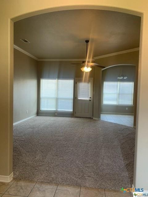 tiled spare room featuring a healthy amount of sunlight and ornamental molding