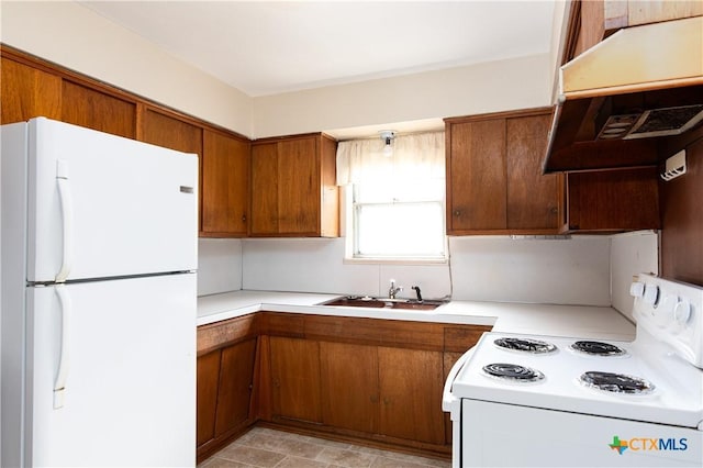 kitchen with brown cabinets, light countertops, a sink, under cabinet range hood, and white appliances