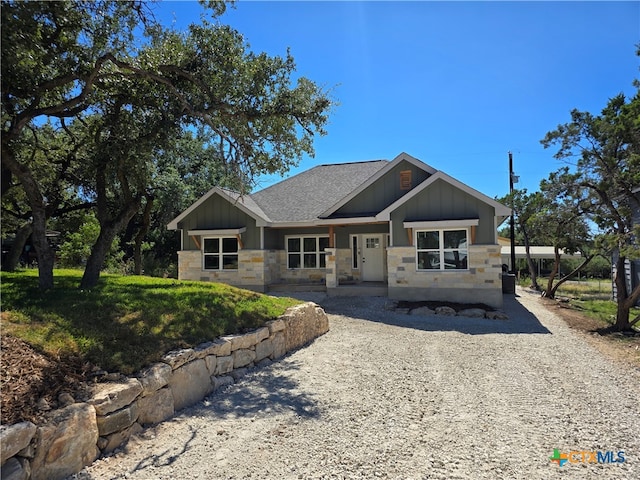 craftsman house featuring board and batten siding, stone siding, and a shingled roof