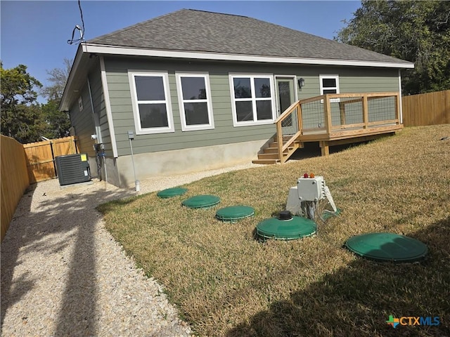 view of front of property featuring roof with shingles, fence, a wooden deck, central AC, and a front yard