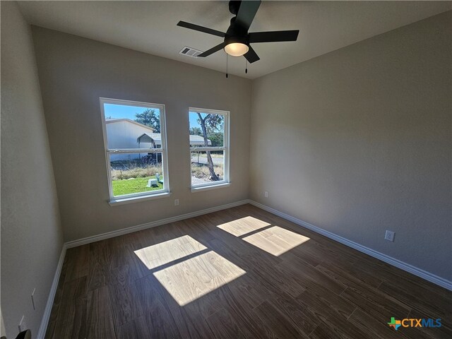 empty room with visible vents, baseboards, and dark wood-type flooring