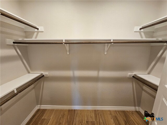 walk in closet with dark wood-style flooring