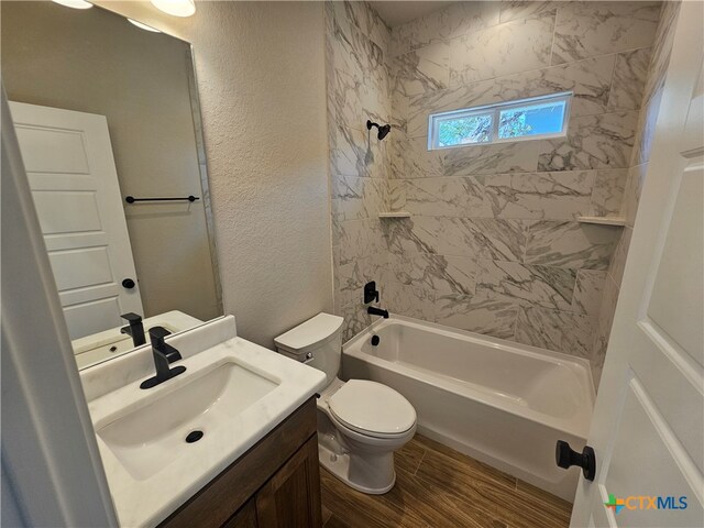 bathroom with shower / bathtub combination, a textured wall, toilet, wood finished floors, and vanity