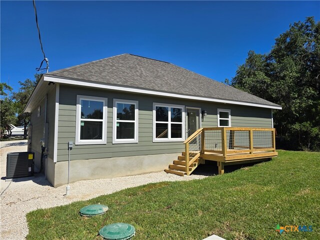 back of house featuring a deck, a yard, a shingled roof, and central AC