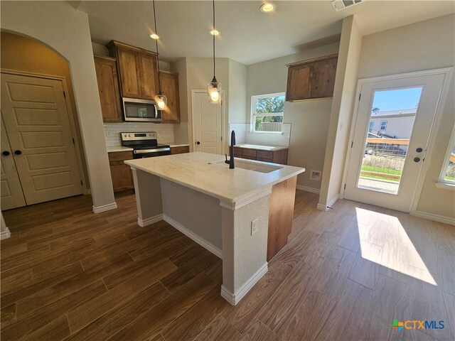 kitchen with stainless steel appliances, dark wood-type flooring, a sink, and tasteful backsplash