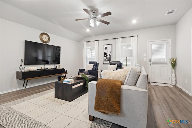 living area featuring lofted ceiling, light wood finished floors, baseboards, and visible vents