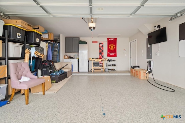 garage with a garage door opener and white fridge