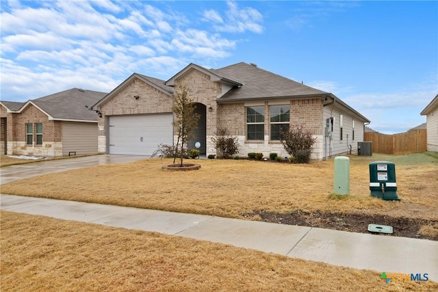 view of front of house with a garage, central AC, and a front lawn