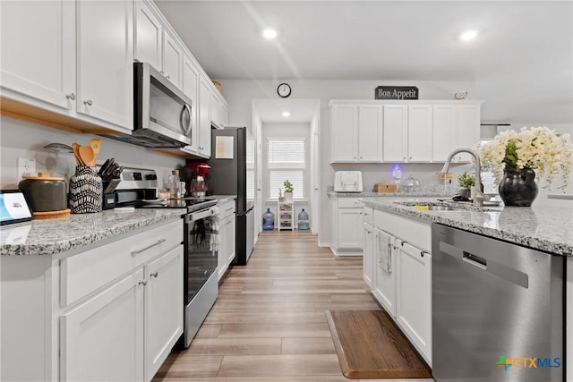 kitchen with recessed lighting, light wood-style flooring, appliances with stainless steel finishes, white cabinetry, and a sink