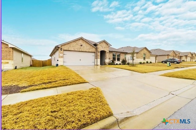 view of front of home with an attached garage, fence, concrete driveway, a residential view, and a front yard