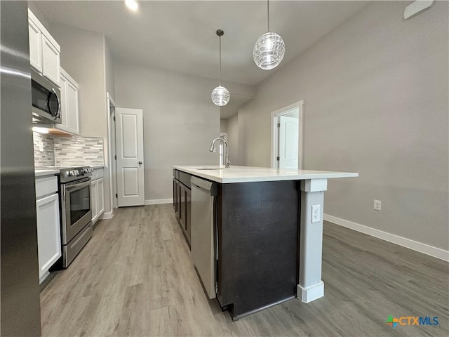 kitchen with decorative light fixtures, tasteful backsplash, white cabinetry, a kitchen island with sink, and stainless steel appliances