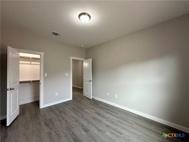 unfurnished bedroom with hardwood / wood-style flooring, a closet, and a spacious closet