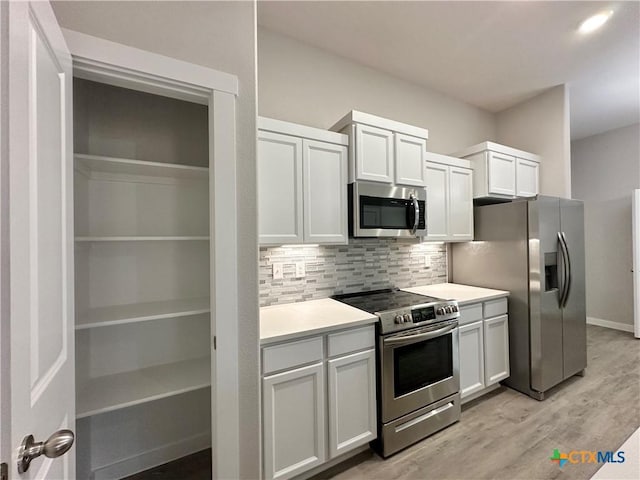 kitchen with white cabinetry, stainless steel appliances, light hardwood / wood-style floors, and decorative backsplash