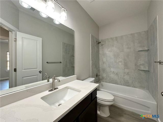 full bathroom featuring tiled shower / bath combo, wood-type flooring, vanity, and toilet