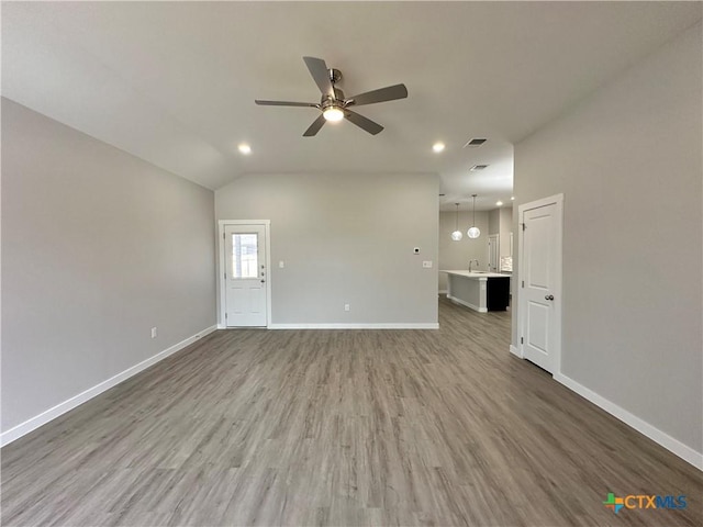 unfurnished living room featuring hardwood / wood-style flooring, ceiling fan, vaulted ceiling, and sink