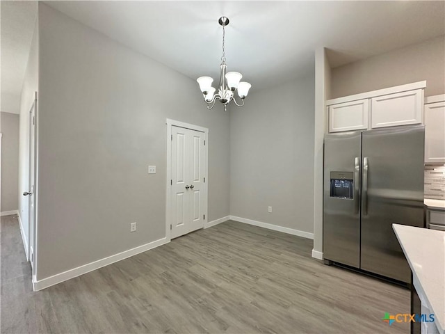 kitchen with white cabinetry, hanging light fixtures, a notable chandelier, stainless steel refrigerator with ice dispenser, and light wood-type flooring