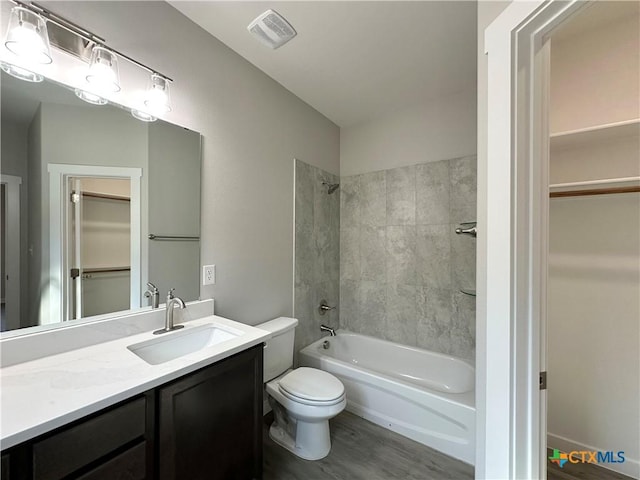 full bathroom with vanity, hardwood / wood-style floors, toilet, and tiled shower / bath