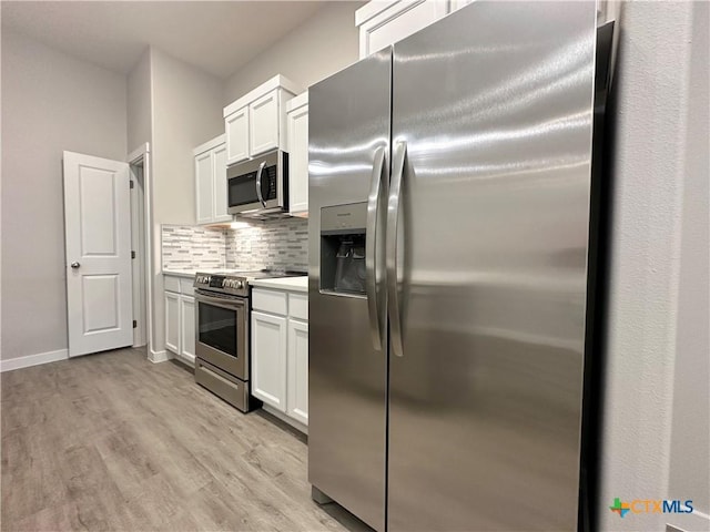 kitchen featuring stainless steel appliances, white cabinetry, light wood-type flooring, and decorative backsplash