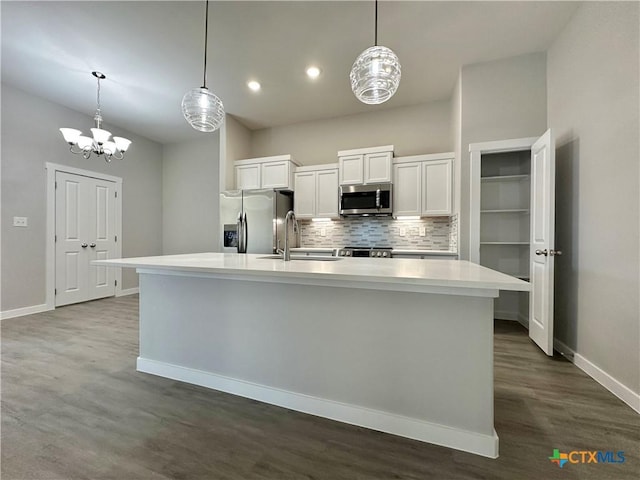 kitchen with sink, stainless steel appliances, tasteful backsplash, an island with sink, and white cabinets