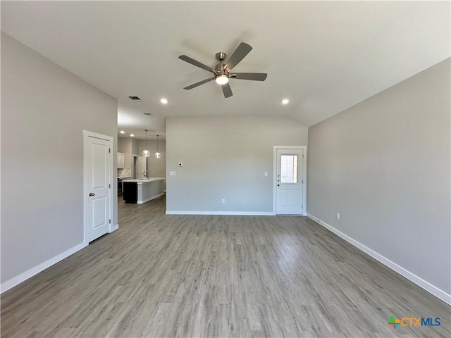 unfurnished living room featuring ceiling fan, vaulted ceiling, and light wood-type flooring