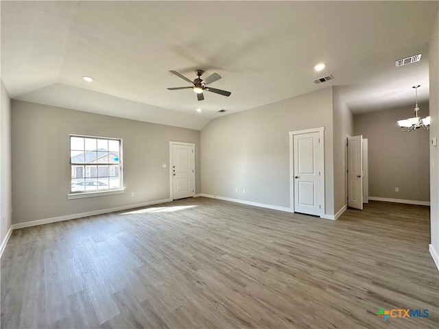 unfurnished room with hardwood / wood-style flooring, lofted ceiling, and ceiling fan with notable chandelier