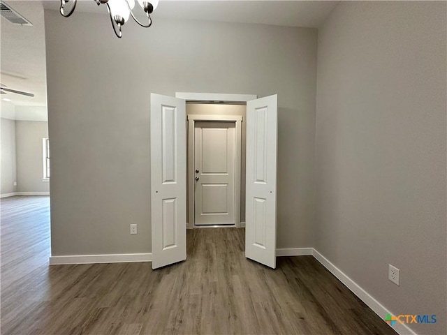 unfurnished room featuring hardwood / wood-style flooring and ceiling fan with notable chandelier