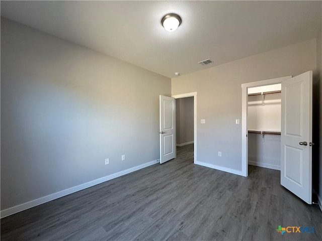 unfurnished bedroom featuring hardwood / wood-style flooring, a closet, and a spacious closet