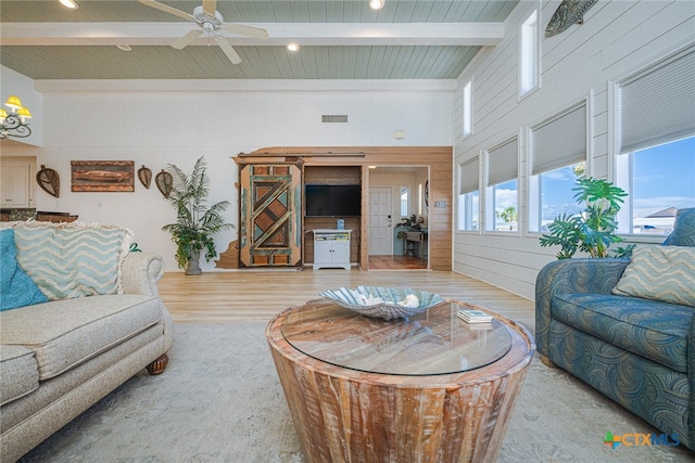 living room featuring a high ceiling, ceiling fan, beam ceiling, and light wood-type flooring