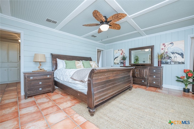 bedroom featuring beamed ceiling, ceiling fan, wooden walls, and light tile patterned floors