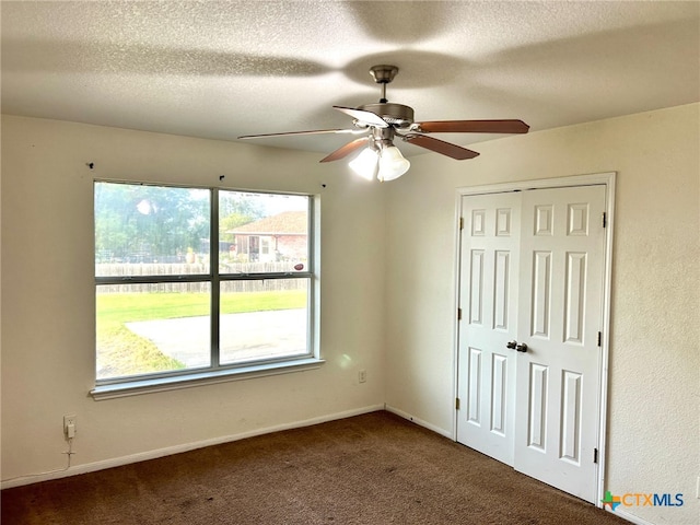 carpeted spare room featuring a textured ceiling and ceiling fan