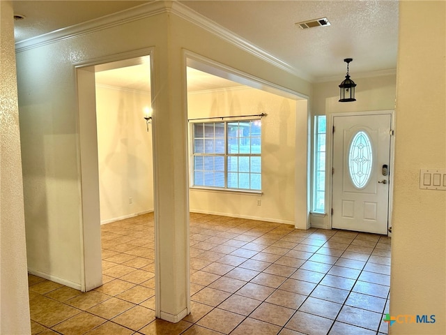 entryway with a textured ceiling, light tile patterned floors, and ornamental molding