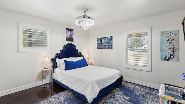 bedroom featuring a chandelier, multiple windows, and dark hardwood / wood-style floors